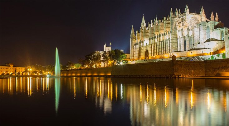 Buildings at night reflected in the waters of Palma, the capital of Mallorca, one of The Balearic Islands in western Spain in the Mediterranean