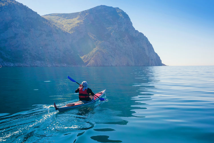 Man kayaking in the calm blue waters of the sea.