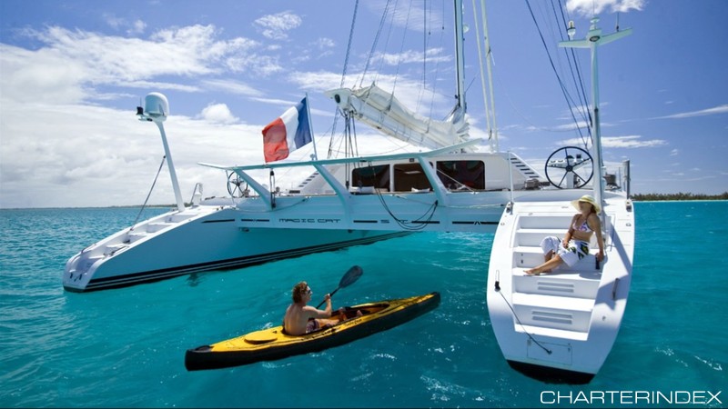 Kayaking up to woman lounging on steps of 82ft sailing yacht Catamaran Magic Cat