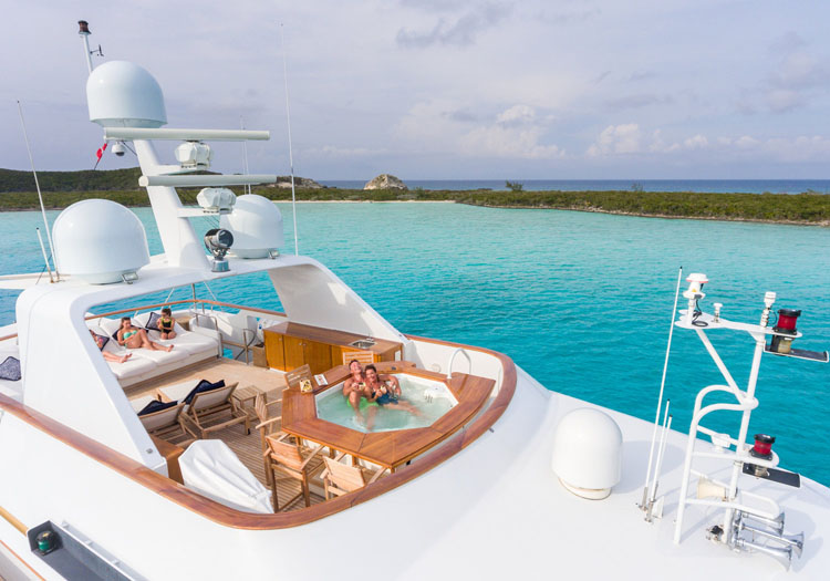 Couple lounging in the Jacuzzi and family on the sundeck aboard the motor yacht LADY J