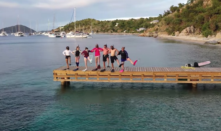 Group of snorkelers from the sailing catamaran LOLALITA dancing on a dock in snorkel gear. Yachting with youngsters and teens.