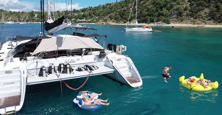 Guest cannonballing giant rubber duck float off sailing catamaran LOLALITA in the British Virgin Islands