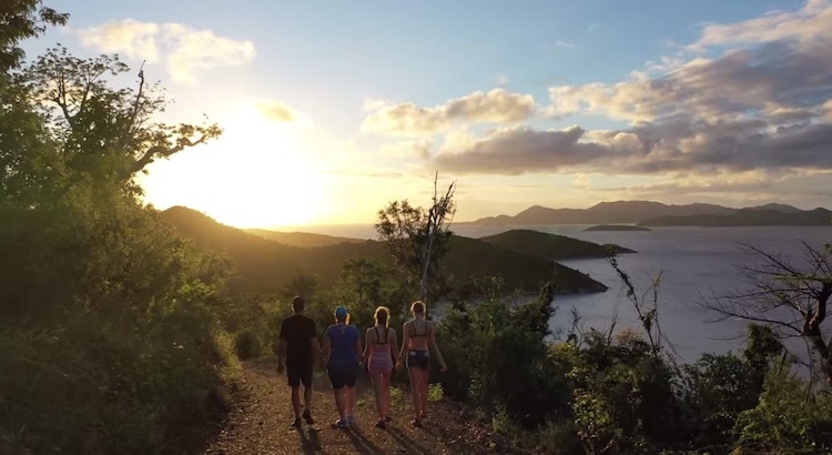 Four family member guests on the sail catamaran LOLALITA take a sunset walk on a hill path in the British Virgin Islands
