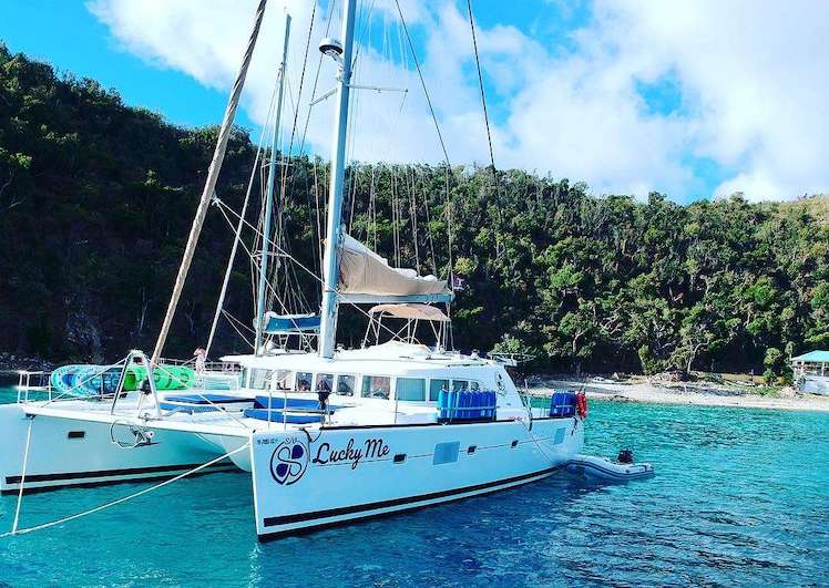 Rear view of 51ft Lagoon sailing catamaran LUCKY ME moored off tropical beach